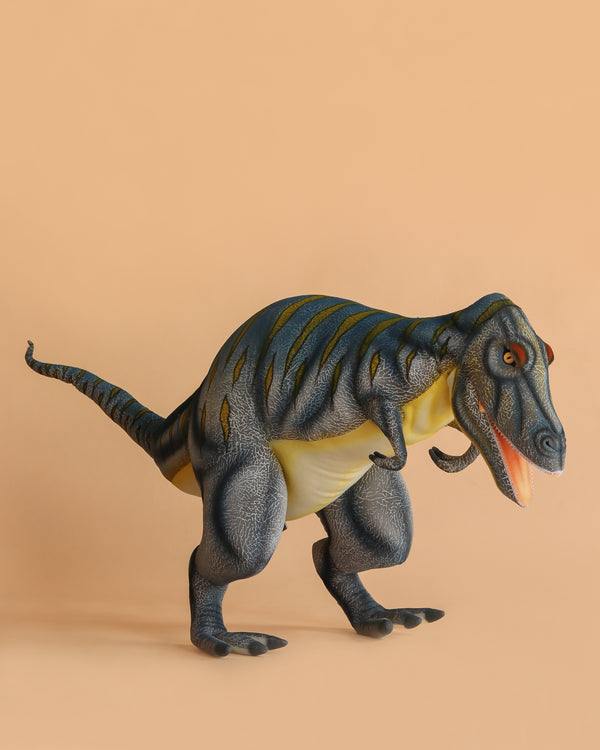 The Giganotosaurus Dinosaur Stuffed Animal, featuring blue stripes and a yellowish underbelly, stands on a plain peach background with its mouth open in a roaring pose.