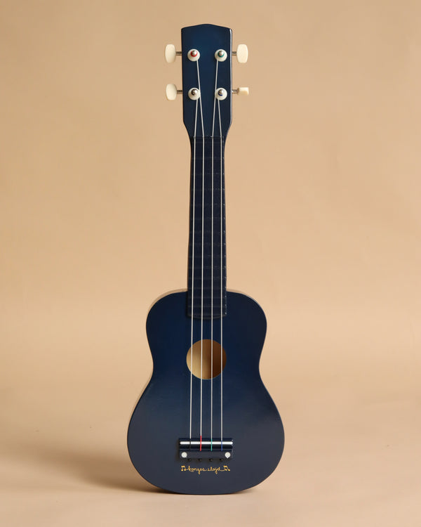 The Konges Sloejd Wooden Ukulele - Midnight stands upright against a plain beige background, featuring a dark blue finish, four white tuning pegs, and 4 strings in a simple, classic design.