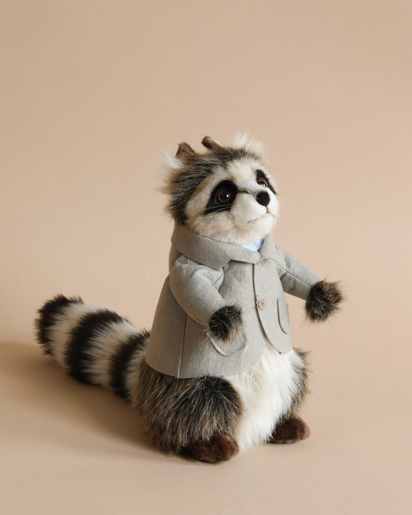 Papa Raccoon With Jacket Stuffed Animal, hand sewn and dressed in a stylish grey coat, stands against a soft beige background, featuring striking black and white fur with an adorable facial expression.
