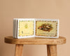 An open copy of *1 Is One by Tasha Tudor* rests on a wooden stool, displaying "5 is five eggs" and "in a pretty round nest"—a charming counting book for fans of Tasha Tudor’s classic style.