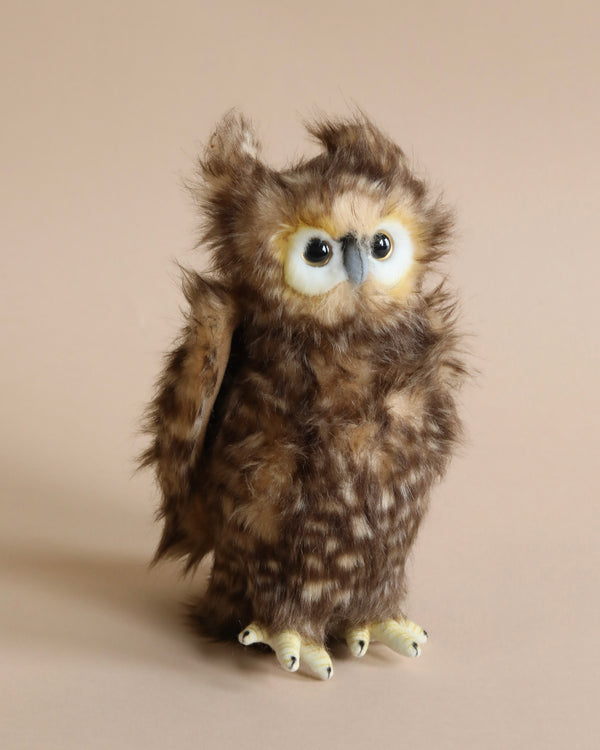 A Owl Stuffed Animal with fluffy brown feathers, large expressive blue eyes, and a quizzical expression. The owl is standing upright on its yellow feet against a plain beige background. This high-quality plush