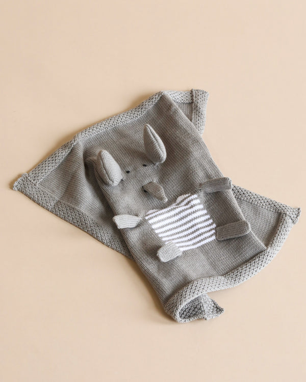 A gray knitted Organic Baby Lovey Blanket - Elephant with a plush rabbit head and a pocket on a light beige background, made from organic cotton.