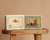 An open copy of 1 Is One by Tasha Tudor sits on a wooden stool, showing a girl drawing flowers and sharing them with her cat, while the text counts nineteen flowers in Tasha Tudor’s signature enchanting style.