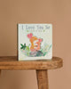 I Love You So by Patricia Hegarty" is a children’s interactive board book with two baby animals snuggling on the cover, shown upright on a wooden stool against a plain beige background.
