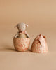 A Maileg Little Lambs Kitchen Set featuring a plush lamb with a pink ribbon is displayed inside a floral Maileg Easter Egg, with the matching lid nearby, all set against a beige background.
