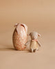 A Maileg Little Lambs Bedroom Set stands beside a floral Easter Egg-shaped box with a pink bow, both displayed against a beige background.