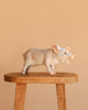 The Pig Stuffed Animal stands on a wooden stool against a plain beige background.