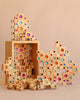 The Bauspiel Colored Stair Blocks - 40 Piece set features vibrant, gem-like wooden blocks stacked in imaginative shapes, with some creative structures built while other pieces are scattered on a neutral background.