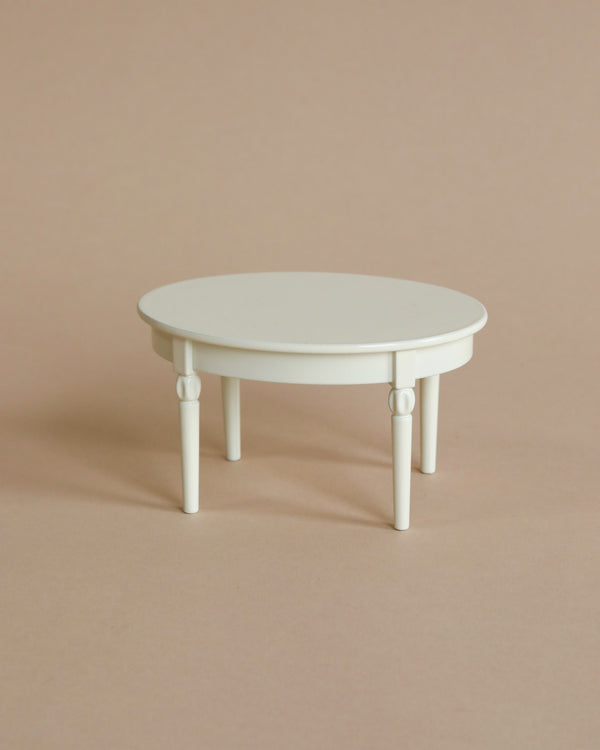 The Maileg Vintage Dining Table, Mouse - Off White is a small, round dollhouse table with four legs, shown on a plain beige background.