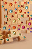 The Bauspiel Colored Stair Blocks - 40 Piece set features vibrant wooden blocks with colorful gem-like stones embedded, stacked and scattered to create a playful, eye-catching display.