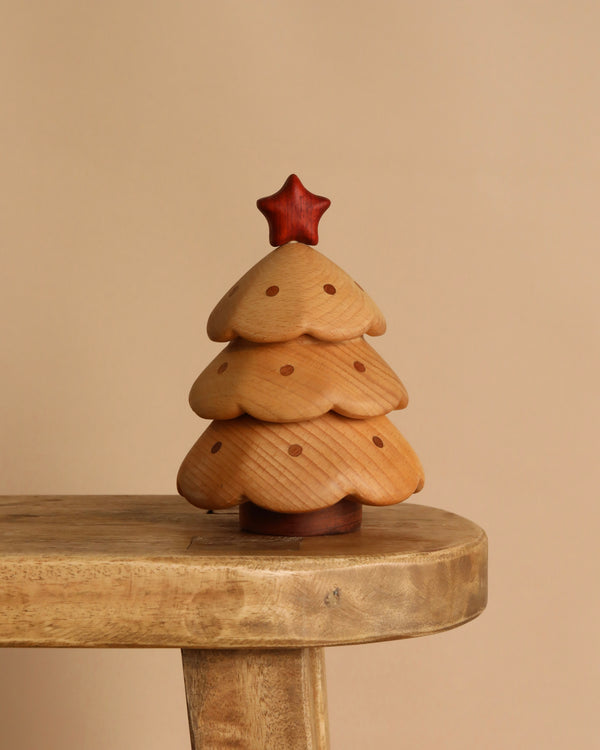 The Christmas Tree Storage Box securely holds a small wooden Christmas tree ornament, featuring a red star, ideal for safe display or storage on a light wood table against a beige background.