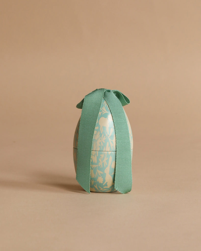 The Easter Basket Gift Set features a decorative egg with a blue floral pattern and a large green ribbon on top, displayed against a plain beige background.