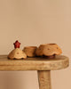 Three small, light wooden Christmas Tree Storage Boxes with scalloped edges and polka dot accents sit on a rustic wooden surface. One features a red, star-shaped handle, perfect for festive storage. The background is solid beige.