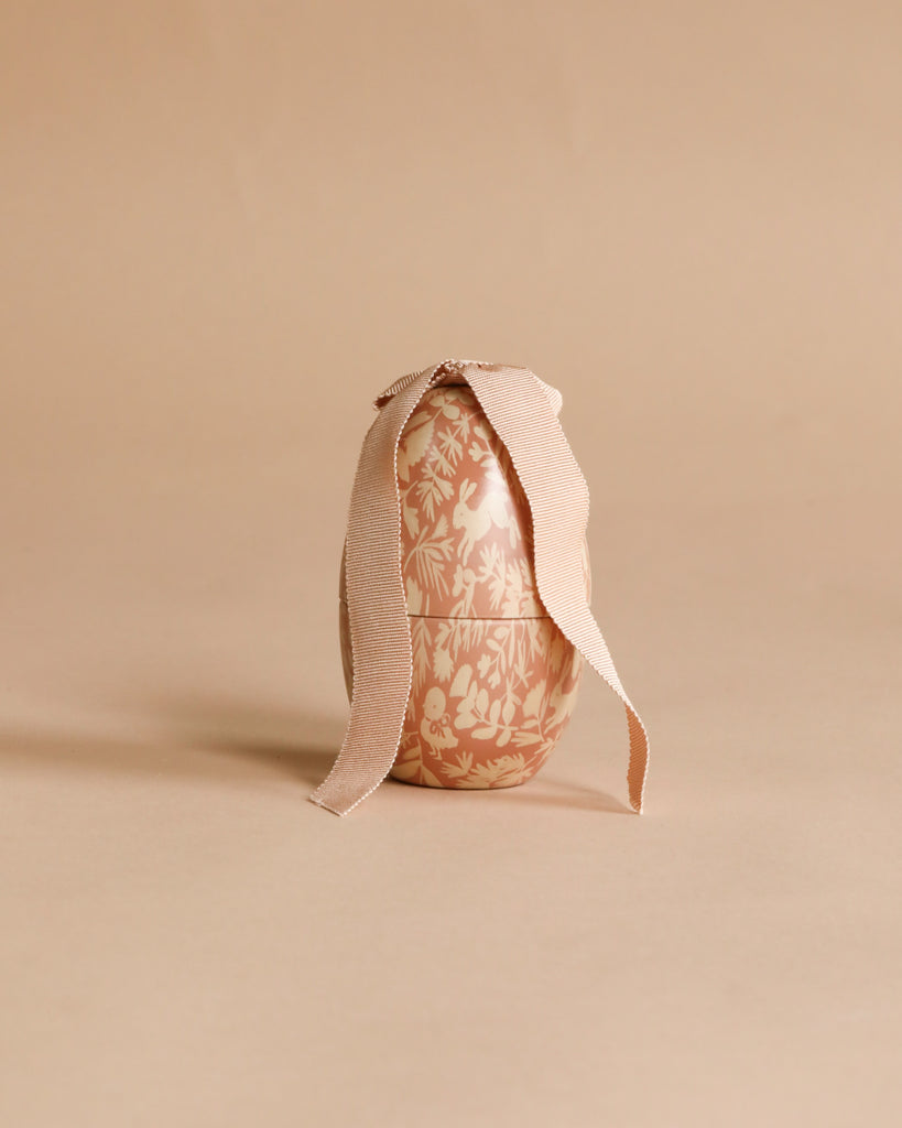 The Easter Basket Gift Set features a decorative egg with a floral design and a textured ribbon tied at the top, beautifully displayed against a neutral beige background.