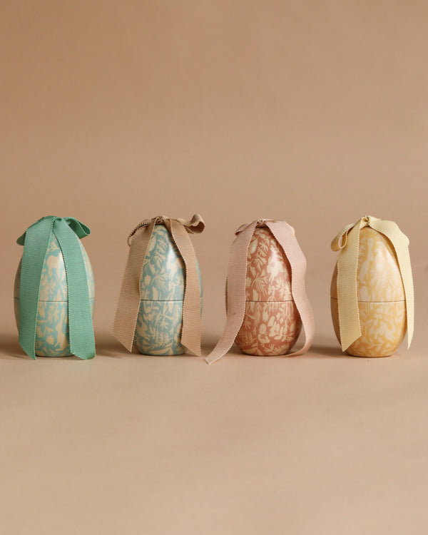 The Maileg Small Easter Egg Set features four pastel floral-patterned eggs, each tied with a matching ribbon bow and arranged on a beige background—perfect for adding charm to your Maileg Easter egg collection.