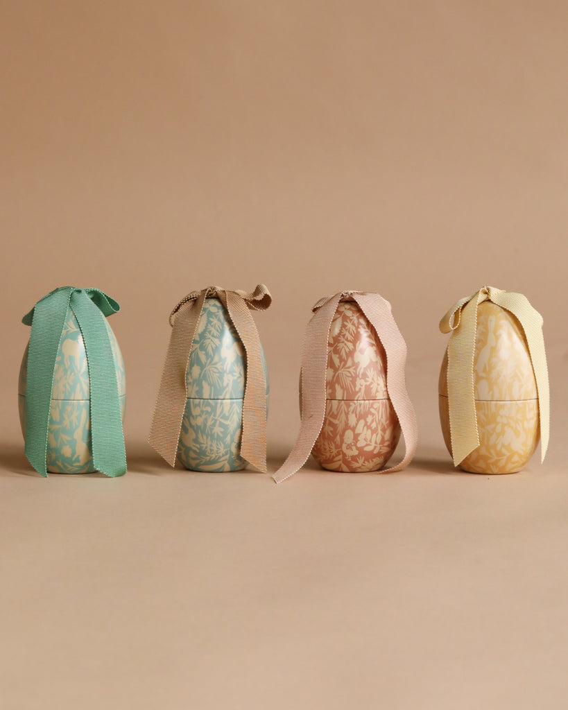 The Maileg Small Easter Egg Set features four pastel floral-patterned eggs, each tied with a matching ribbon bow and arranged on a beige background—perfect for adding charm to your Maileg Easter egg collection.