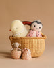 The Maileg Easter Basket Set features a woven basket holding a plush yellow duck and a knitted doll, with a Maileg Easter Egg beside them. In front, a fabric bunny and two pink patterned eggs rest on the beige background.