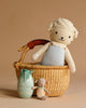 The Easter Basket Set includes a hand knit lamb doll in overalls, a Maileg Easter Egg with a green bow, and a tiny stuffed bunny, arranged on a beige background.