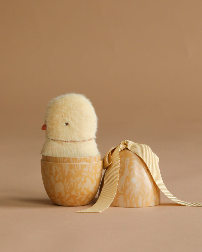 The Maileg Easter Egg with Mini Chick features a fluffy yellow plush inside a floral egg container with a matching ribbon lid—perfect as an Easter gift set.