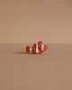 A small clownfish figurine from the Handmade Holzwald Ocean Animals Set sits on a plain beige surface with a matching background, showcasing the charm of artisanal toys.