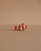 A Handmade Holzwald Clownfish, featuring orange and white colors with black stripes, sits on a plain beige surface with a matching background—an adorable addition to any Holzwald wooden toy collection.