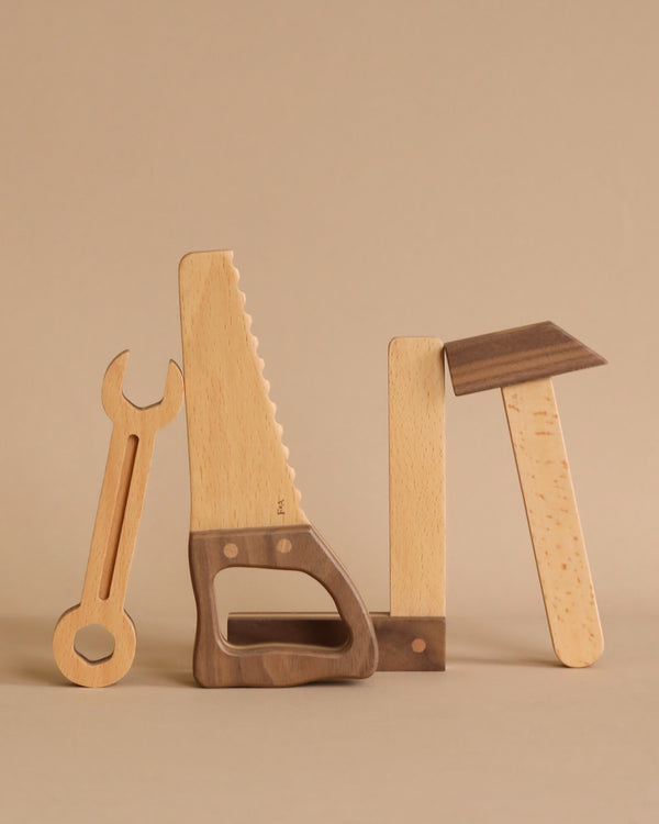 Heirloom quality Wooden Tool Set, creatively assembled to spell the word "tool" on a plain beige background.