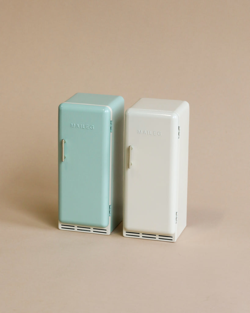 Two Maileg Miniature Fridges, one mint green and one white, each labeled "maileg," standing together against a neutral beige background. These are models from the House of Miniature collection.
