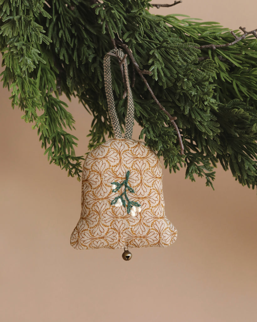 The Maileg Ornament - Two Bells, ideal for a Maileg-inspired Christmas tree, hangs elegantly from a green branch. It showcases a charming floral pattern with an embroidered sprig and a small silver bell at the bottom against a soft beige background.