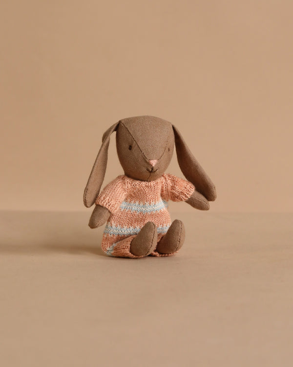 The Maileg Bunny, Micro - Brown wears a dusty rose knitted suit and sits upright, making it a charming addition to your miniature dollhouse or perfect for pairing with Maileg accessories.