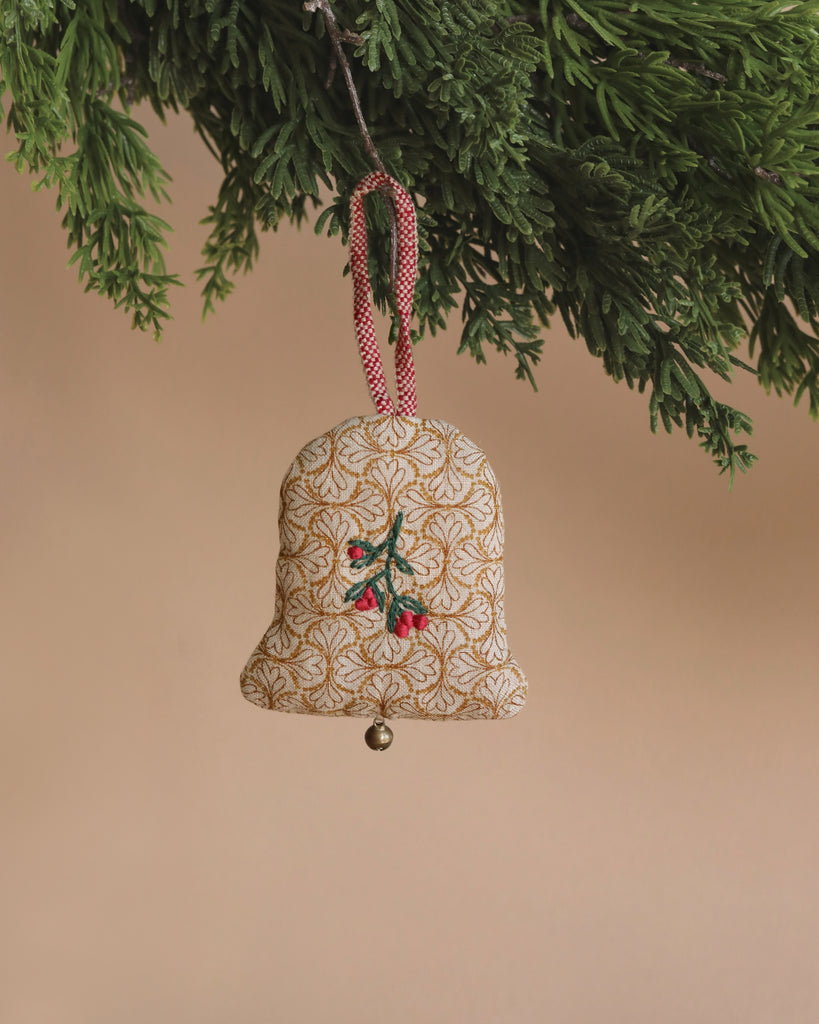 The Maileg Ornament - Two Bells features a fabric bell adorned with embroidered red berries and green leaves, hanging elegantly from a Christmas tree branch by a red checkered loop. Set against a soft beige background, this ornament is sure to be one of the charming pieces in your collection.