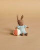 The Maileg Micro Bunny With Ball - Brown - Blue features a soft brown bunny in a blue outfit with magnetic hands, sitting beside a small white and orange ball—an adorable addition to any bunny collection.