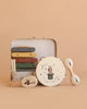 The Konges Sloejd Music Set - Circus, featuring a xylophone, tambourine, maracas, and castanet adorned with charming animal illustrations, is arranged in front of an open musical suitcase on a beige background.
