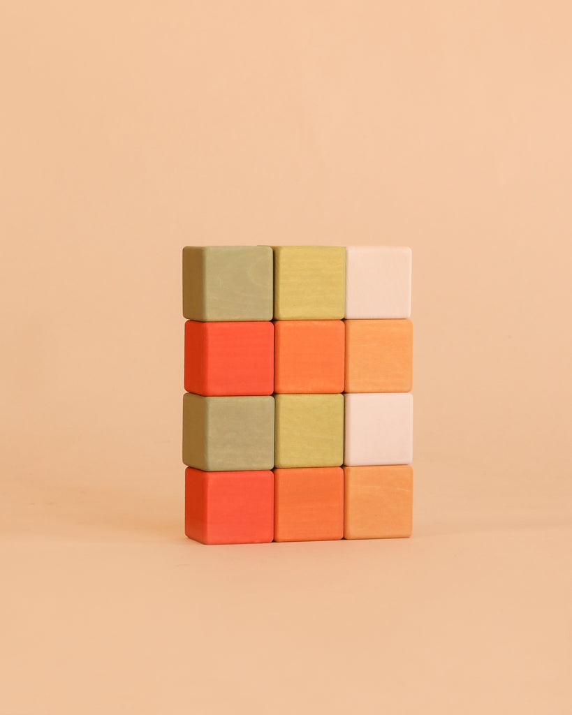 Four rows of three Sabo Concept Mini Wooden Blocks - Flower Meadow, in shades of green, orange, yellow, and white, are neatly stacked against a plain beige background—an engaging educational toy designed to help develop fine motor skills.