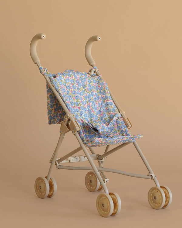 The Konges Sloejd Doll Stroller - Fiola features a lightweight, retro design with curved handles, a charming Fiola print fabric seat, and four pairs of small wheels, all in stylish beige.