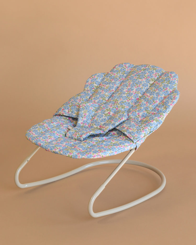 The Konges Sloejd Doll Bouncer - Rose Flower features a white metal frame and a rose floral-patterned seat, shown against a plain beige background—an ideal addition to any doll accessory collection.