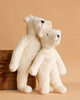 Two Senger Naturwelt Stuffed Animal - White Bears stand side by side, leaning against a wicker basket on a solid light brown background—a charming display of these sustainable plush toys.