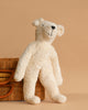 The Senger Naturwelt Stuffed Animal - White Bear, with floppy arms and legs, leans against a wicker basket on a beige background. This charming and eco-friendly plush toy is perfect for sustainable cuddles.
