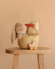The Easter Basket Gift Set, featuring a Maileg Plush Bunny, patterned cushion, and wooden toy in a woven basket on a stool, is displayed with a Rolling Duck on wheels against a solid beige background.