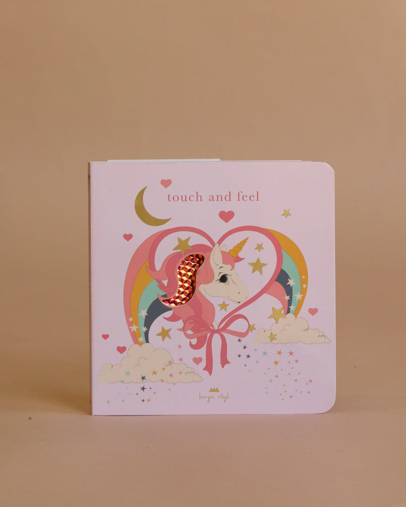 The Easter Basket Gift Set features a pink children's "touch and feel" book with a unicorn, rainbow, stars, clouds, and moon on the cover. The unicorn's mane has a textured red patch for tactile fun—ideal for little Maileg Unicorn fans.