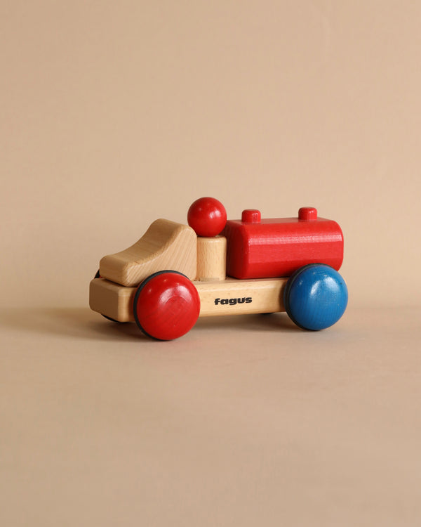 A Fagus Wooden Tanker Truck - Mini Series with colorful wheels and body parts, featuring a mix of blue, red, and natural wood colors, on a plain background.