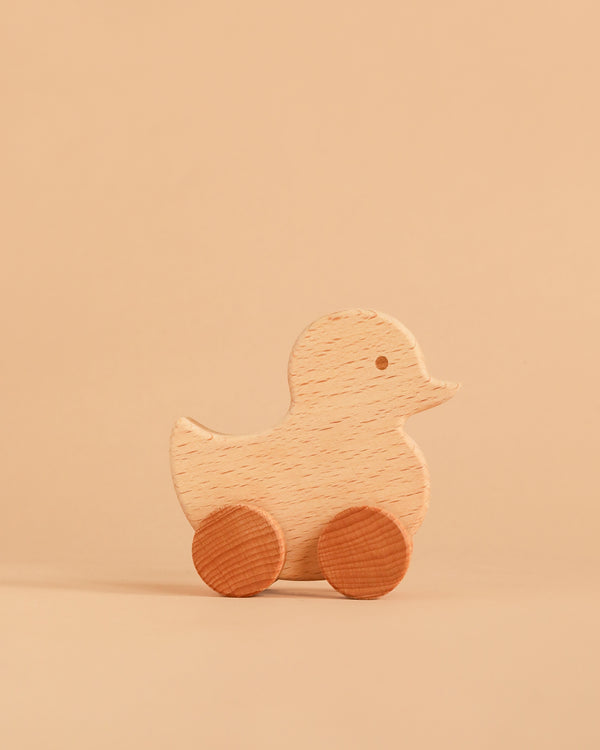 The Sabo Concept Rolling Duck - Natural, a wooden toy with round wheels crafted from natural materials, sits on a beige surface against a matching beige background.
