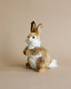 A plush toy rabbit with brown and white fur, standing upright on a beige background, next to an Easter Basket Set - Trunk.