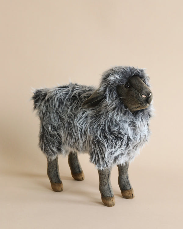 A Sheep Stuffed Animal with fluffy gray fur, standing against a soft beige background. The toy, an example of hand-sewn plush animals, features realistic details including textured hooves and a gentle, in