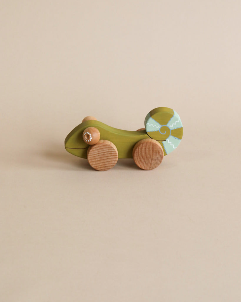 Wooden green chameleon with wooden wheels. Beige background. 
