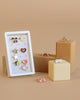 The Konges Sloejd 12 Pack Ring Set features colorful, whimsical adjustable rings with motifs like cherries, moon, stars, heart, bunny, and rainbow—perfect for tiny fingers and arranged on a white card against a neutral background.