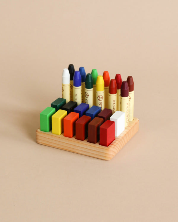 A neatly arranged set of colorful Stockmar crayons and wooden building blocks on a Crayon Tray For Stockmar -12 x 12 Slots against a beige background.