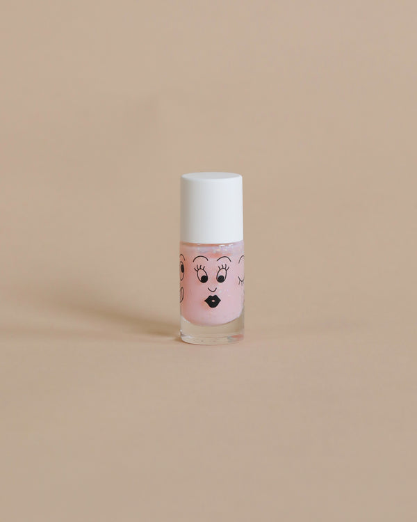 A small bottle of pink, washable Nailmatic - Nail Polish - Polly with a cute face drawn on it, featuring eyes with lashes and lips, against a plain beige background.