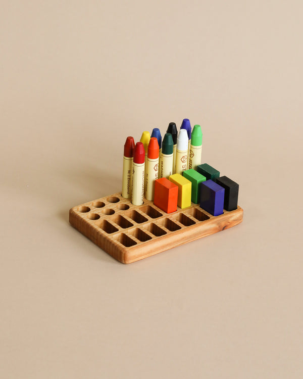 An array of colorful Crayon Tray For Stockmar -16 x 16 Slots neatly arranged in a Linden wood holder on a beige background.