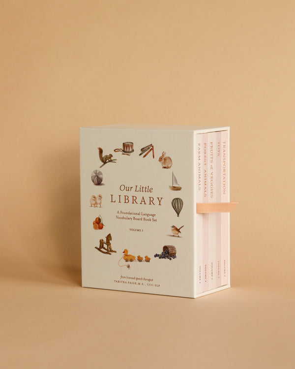 A set of Our Little Library Book Box Set displayed against a plain beige background. The box is open slightly to show the books inside, each featuring illustrated baby vocabulary items.