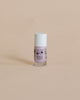 A small bottle of pink, vegan cruelty-free Nailmatic Elliot glitter nail polish with a cartoon face drawn on it, standing against a plain beige background.